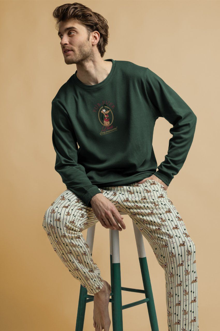 Modelo con pijama de hombre Disney Pluto Stay Pawsome 64928, con camiseta verde de manga larga con dibujo de Pluto y pantalón largo claro estampado.
