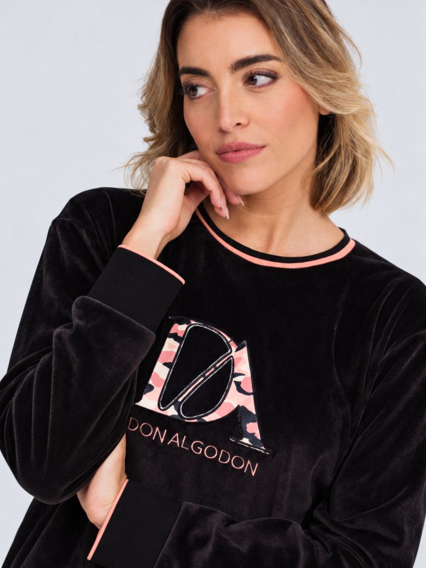 Modelo con pijama Don Algodón DA26W441 de mujer, camiseta negra con logotipo y pantalón de leopardo rosa con puños.
