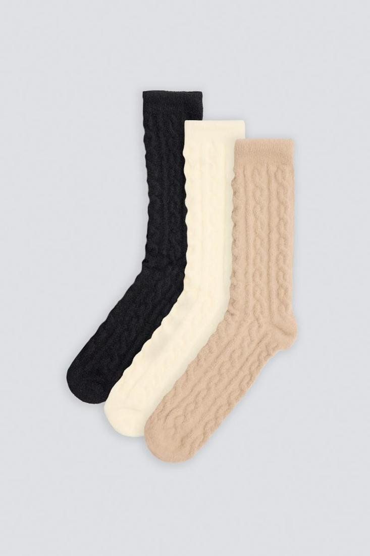 Tres calcetines de mujer Ysabel Mora 12137 con dibujo de trenzas en relieve, en colores negro, crudo y beige.