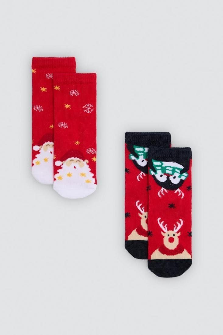 Dos pares de calcetines navideños de bebé, uno rojo con Papá Noel y otro con renos y detalles oscuros.
