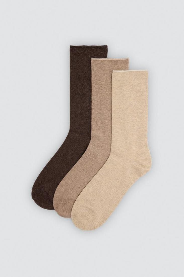 Detalle de calcetines lisos de hombre sin puño Ysabel Mora 22730, superpuestos en tonos beige y marrón.
