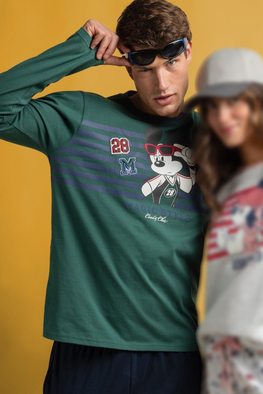 Modelo con pijama de hombre Disney Magic Style 64916, con camiseta verde de manga larga con dibujo de Mickey Mouse y pantalón largo oscuro.