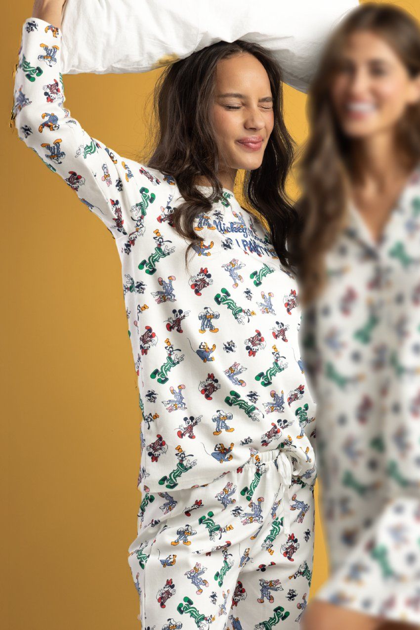 Modelo con pijama de mujer Disney PJ Party 64692 en color crudo, con camiseta de manga larga y pantalón largo con estampado de personajes Disney.