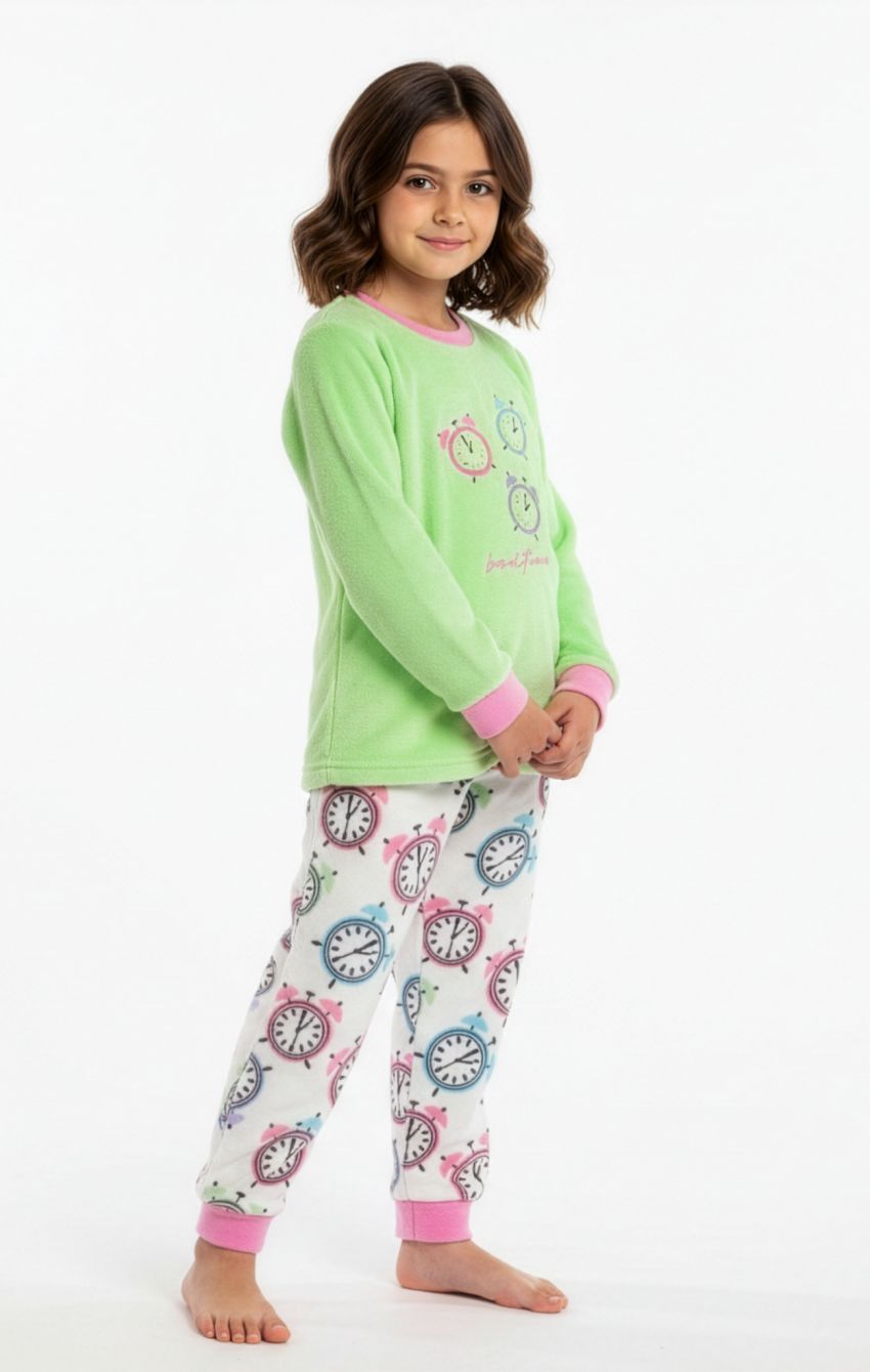 Niña con pijama de coralina KN 491, camiseta verde con dibujos de despertadores y pantalón claro estampado de relojes multicolor con puños rosas.