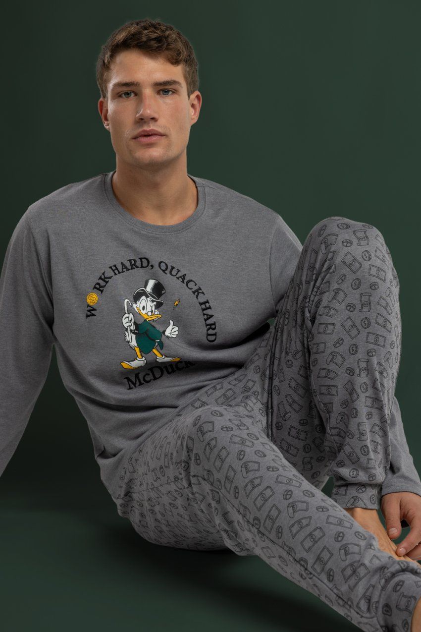 Modelo con pijama de hombre Disney Work Hard Quack Hard 64909, con camiseta gris jaspeada de manga larga con dibujo frontal y pantalón largo estampado.