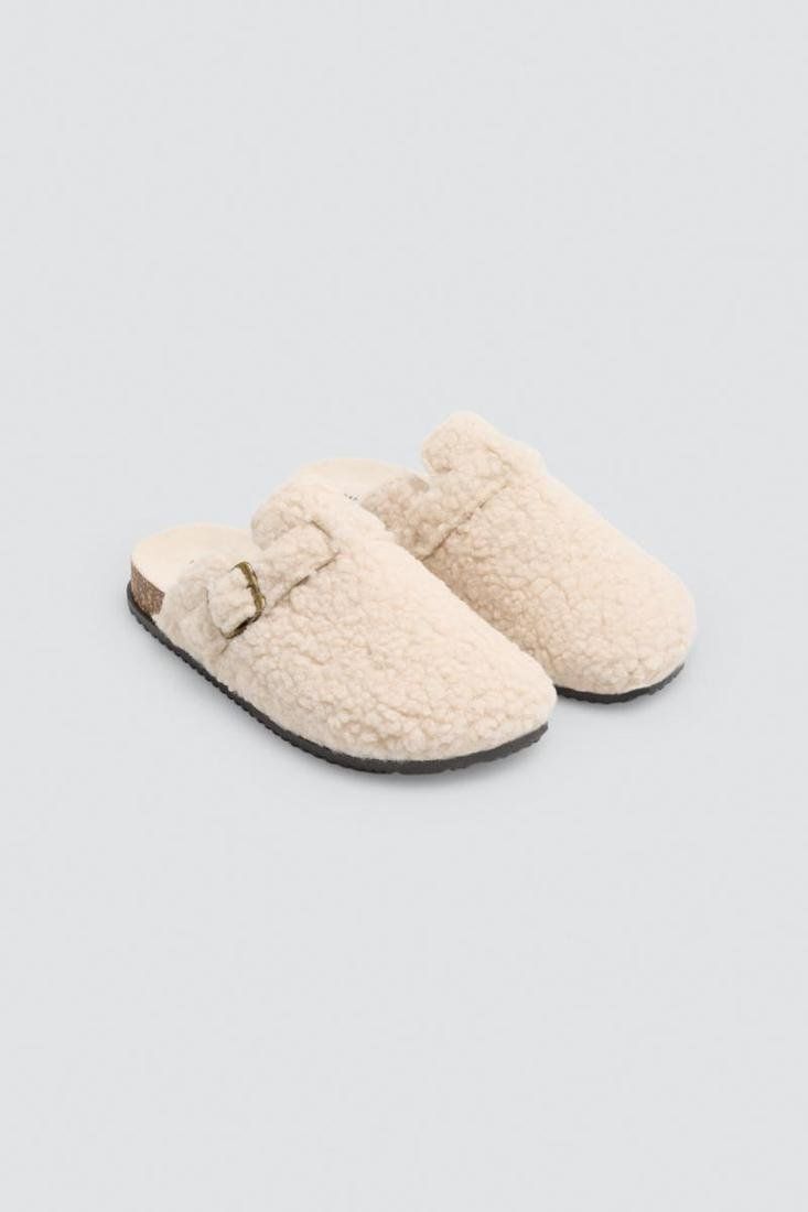 Vista superior de las zapatillas de casa para mujer Ysabel Mora 14191 en tono crudo, con acabado de borreguito, detalle de hebilla lateral y talón abierto.