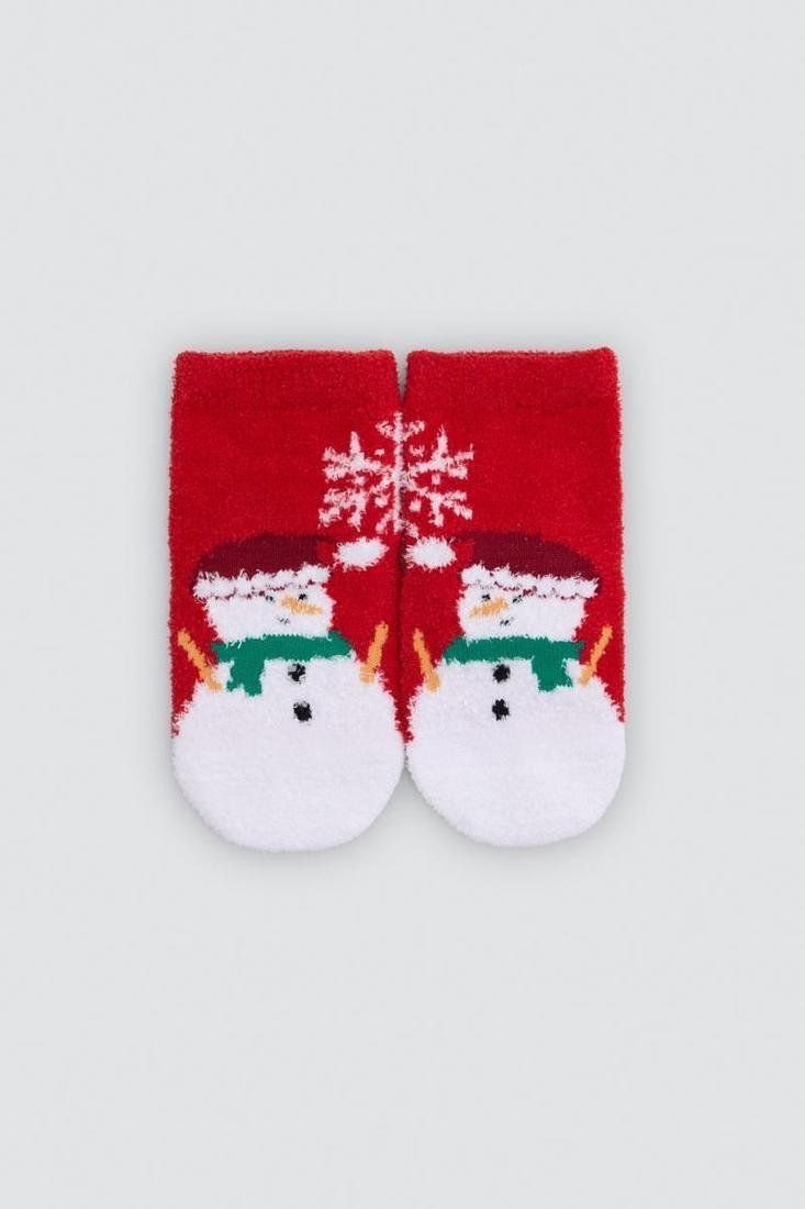 Estuche rojo de calcetines de bebé Ysabel Mora con ilustración de Papá Noel, copos de nieve y ventana decorativa.