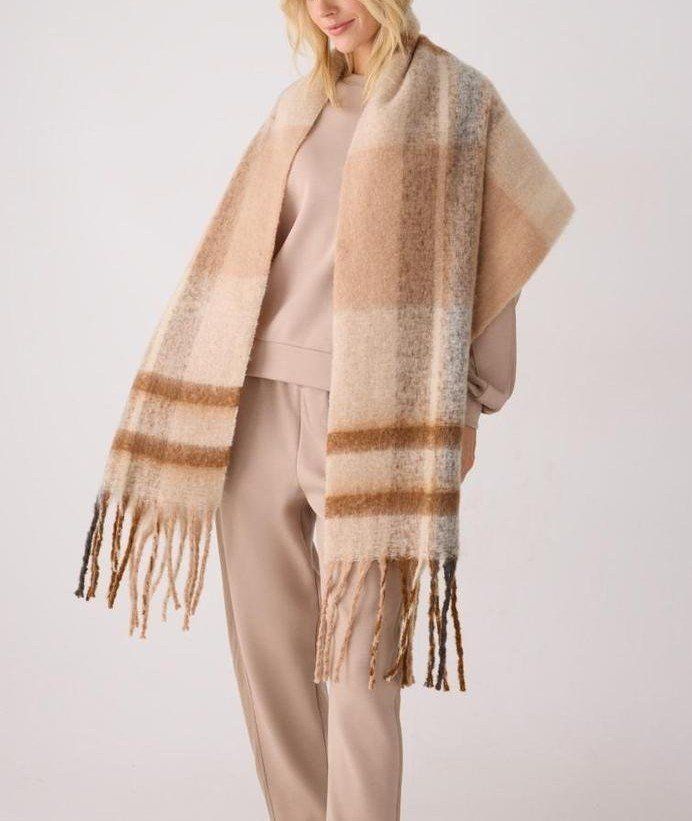 Modelo con pashmina Ysabel Mora 70714 sobre los hombros, de cuadros grandes en beige, camel, crudo y gris, con flecos en los extremos.